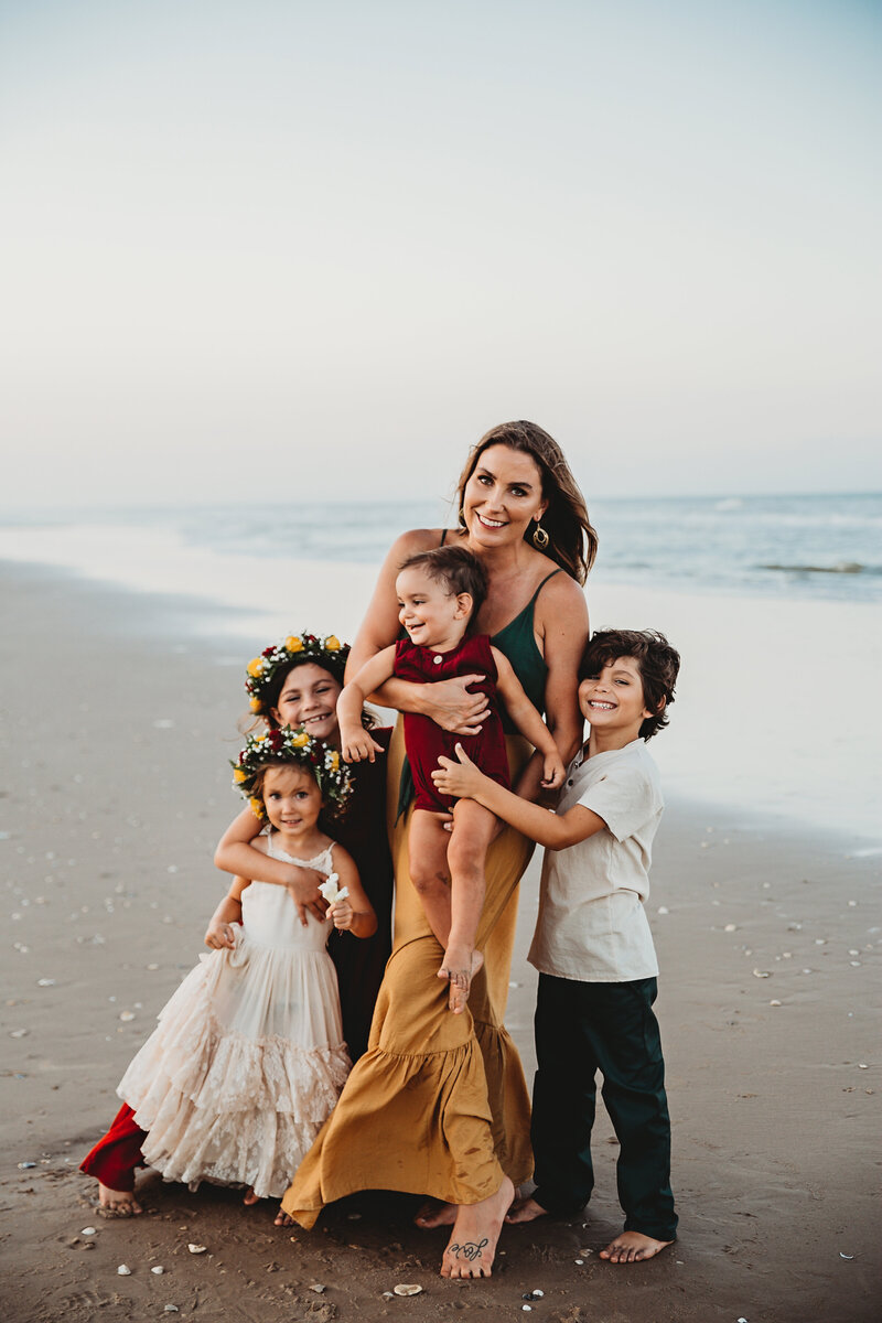 Mom and four kids wearing jewel tones and flower crowns on the beach on south padre island