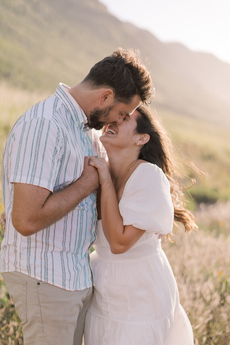 Couple smiles and holds hands on the shores of oahu Hawaii for wedding