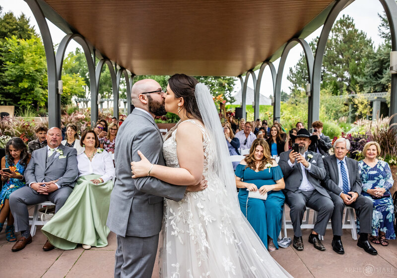 Couple Kiss in front of their family and friends at the Annuals Pavilion at Denver Botanic Gardens