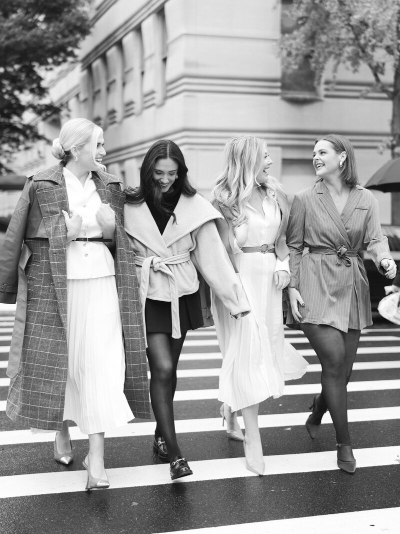 The team of international wedding planners at Passera Events, showing four women in black dresses in front of a floral display of white flowers.