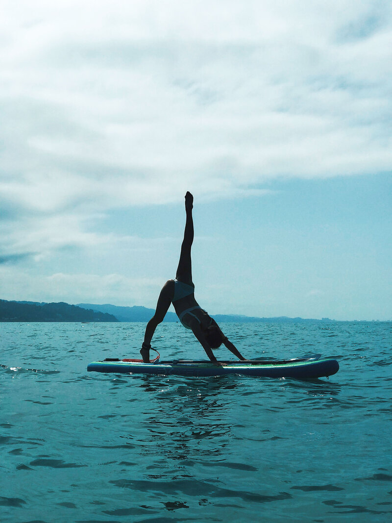 A photo of a women stretching on a paddle board