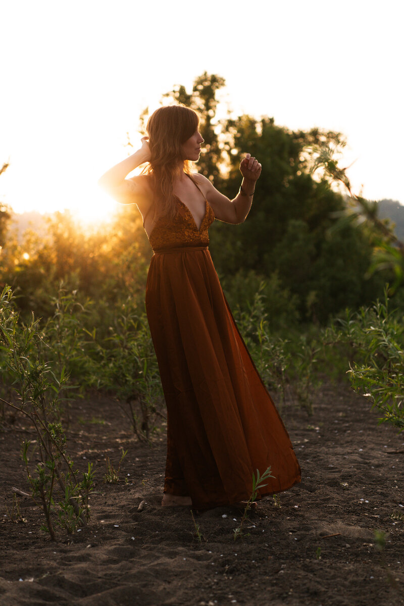 mentor, healer, guide with her hand behind her head in a green field with a sunburst behind her