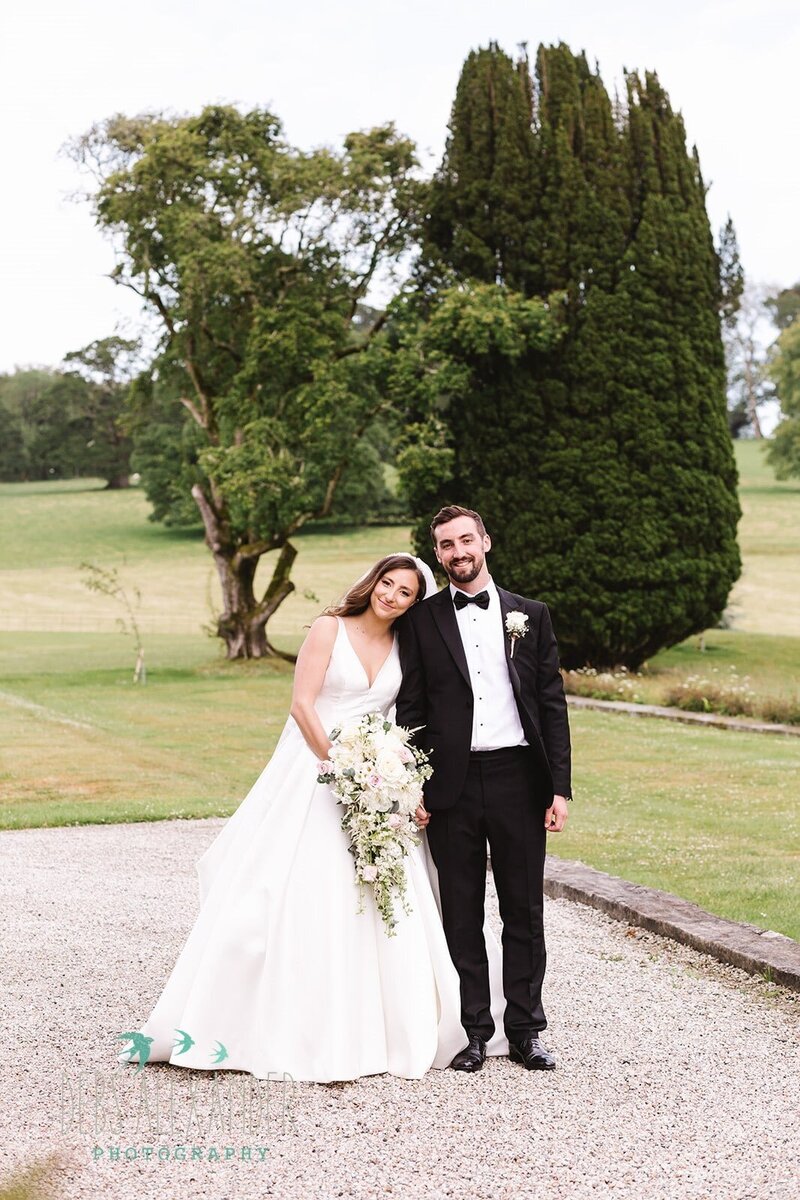 Bride in a white satin dress and a groom in black tie for this wedding in Cornwall