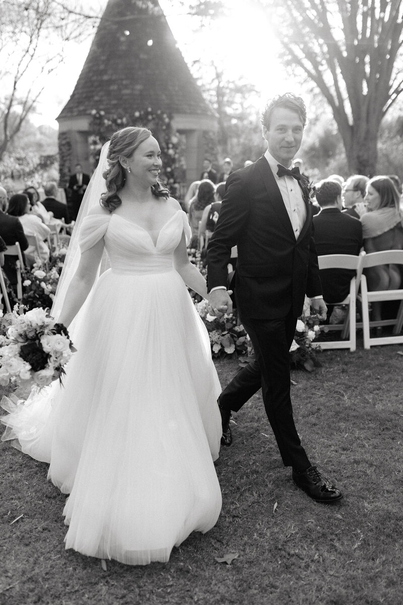 November wedding at Graylyn Estate, designed and planned by Charming Carolina — bride and groom walk hand in hand down the aisle after their garden ceremony in the White Garden.