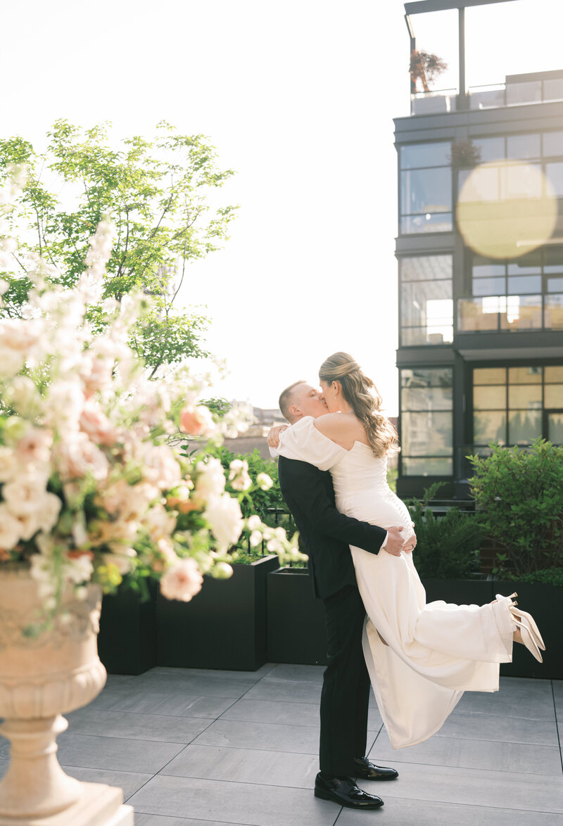 A groom picks up his bride on a rooftop at their wedding in Chicago