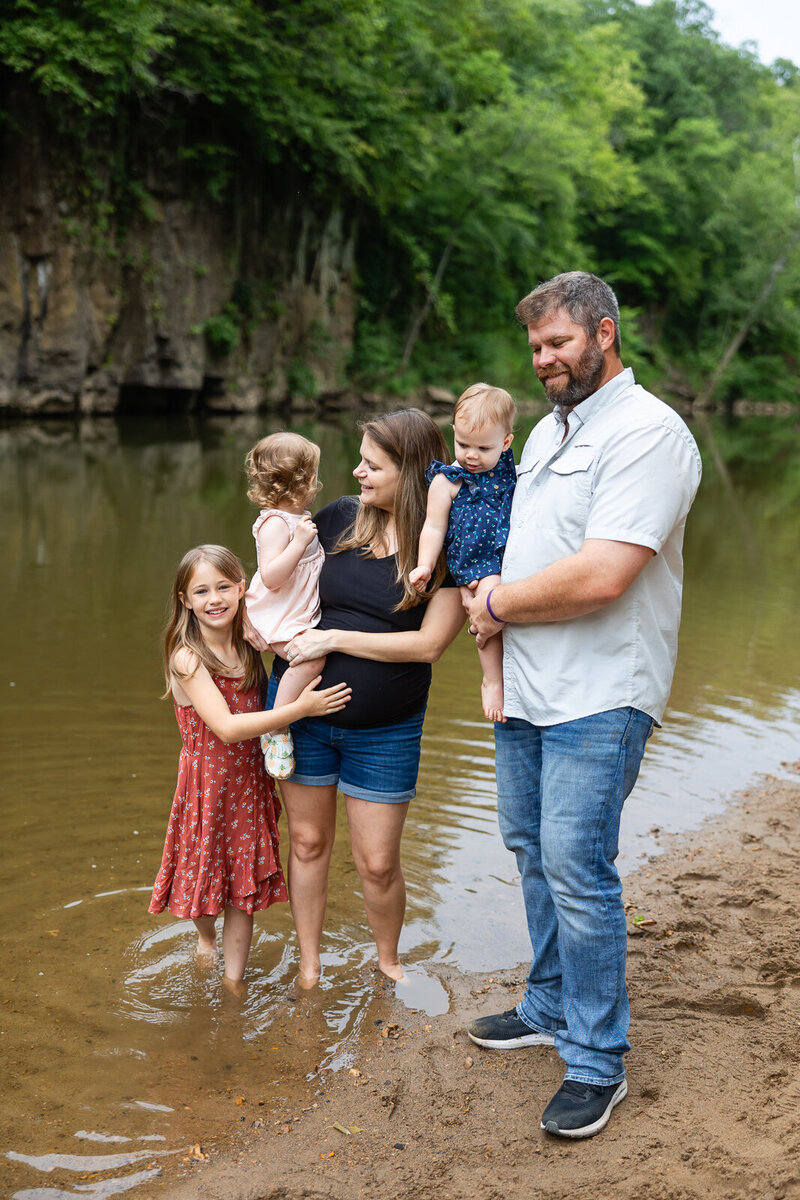 Family of baby, toddler, child and parents in the creek during a lifestyle family session in Farmington, Missouri. 