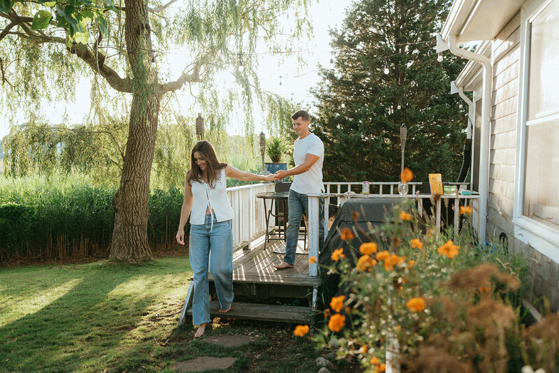 couple walking in backyard during at home engagement photos, captured by Elsie Goodman, an NYC engagement and couples photographer
