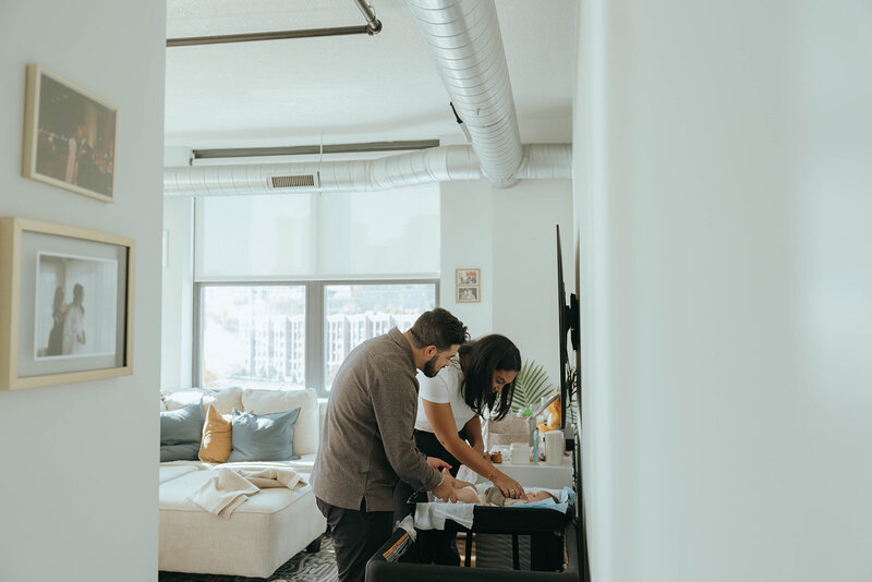 couple changing baby on table during in home newborn photos captured by NYC newborn photographer Elsie Goodman 