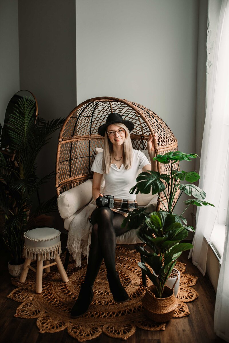 Photographer sitting in an egg chair holding her camera