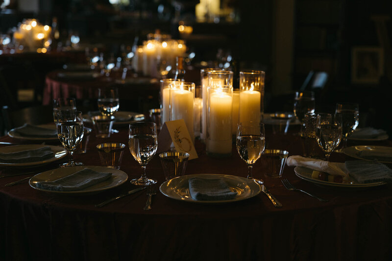 Lit candles and table settings at a wedding planned by Eugene wedding planners Birdie June Events and Rentals. 