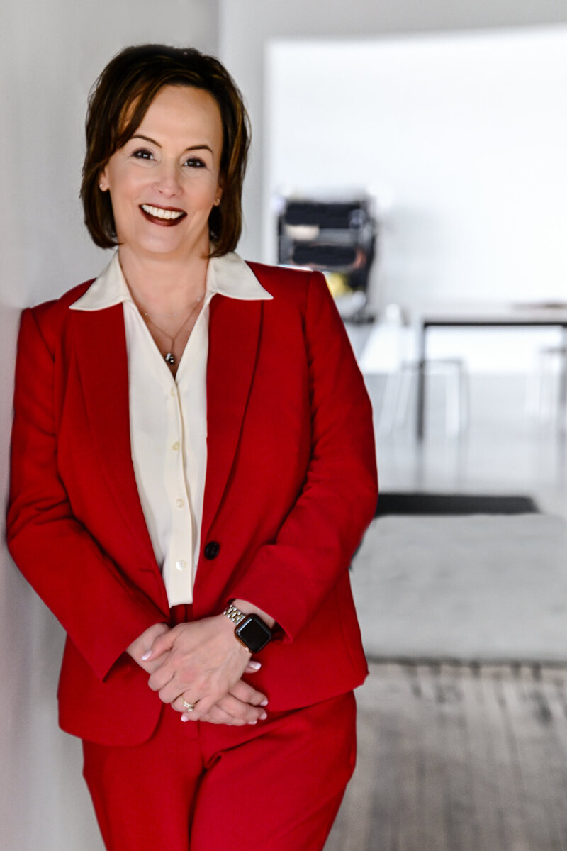 alt="Jennifer Petersen, attorney at JRP Mediation and Employment Law, smiling in a red suit jacket with white blouse against a bright office background"