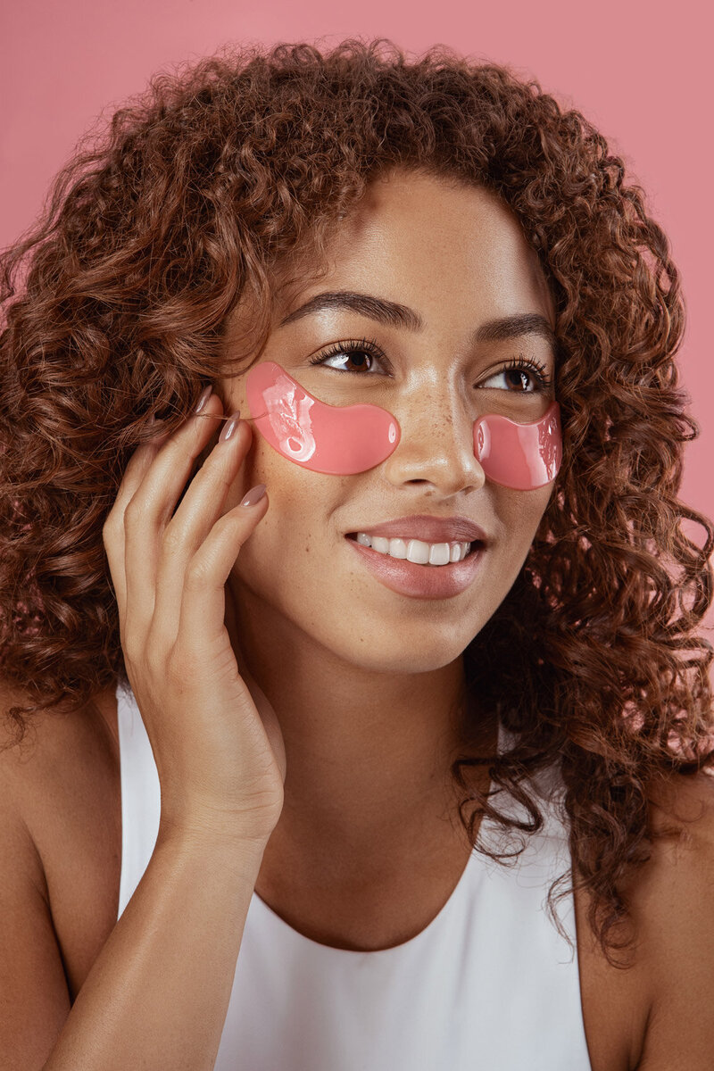 Jayla applying a pink skincare mask to her cheeks with a joyful expression, captured by Ylva Erevall.