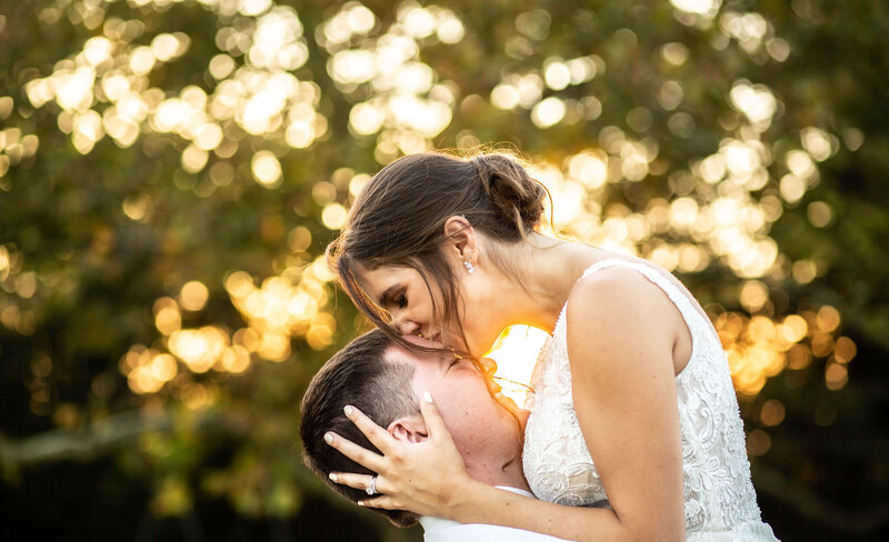 Bride kisses groom on the forehead during a sunset at Bohemia Overlook, Maryland wedding