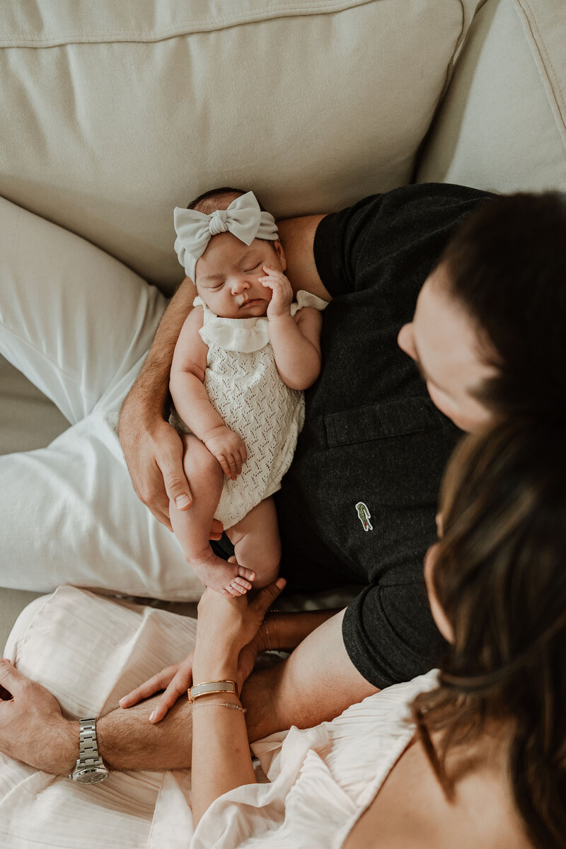 Mom and dad looking at newborn baby girl while she sleeps