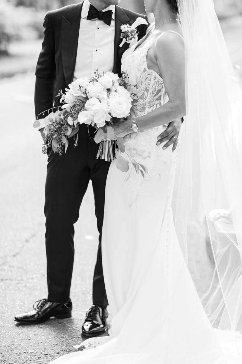 Black and white photo of groom with arm around bride