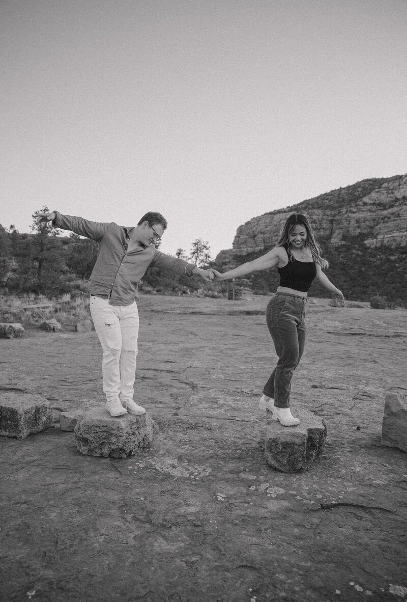 couple holding hands climbing on rocks at desert engagement session