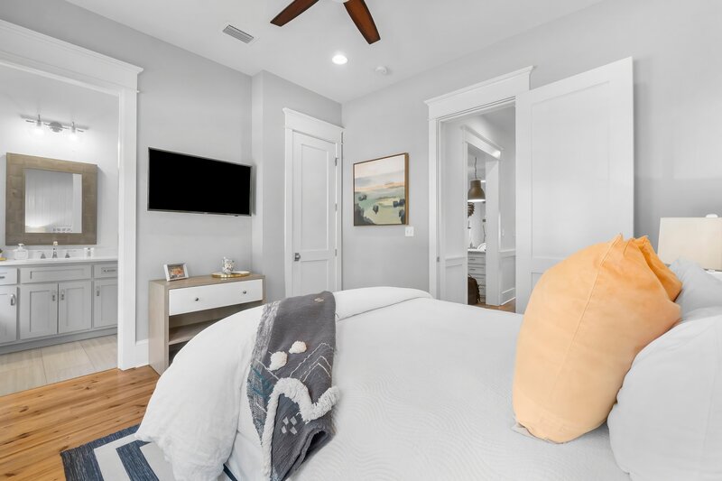 Queen bedroom with wall-mounted smart TV and private bath at Tangerine Dream, close to Grayton Beach and 30A.

