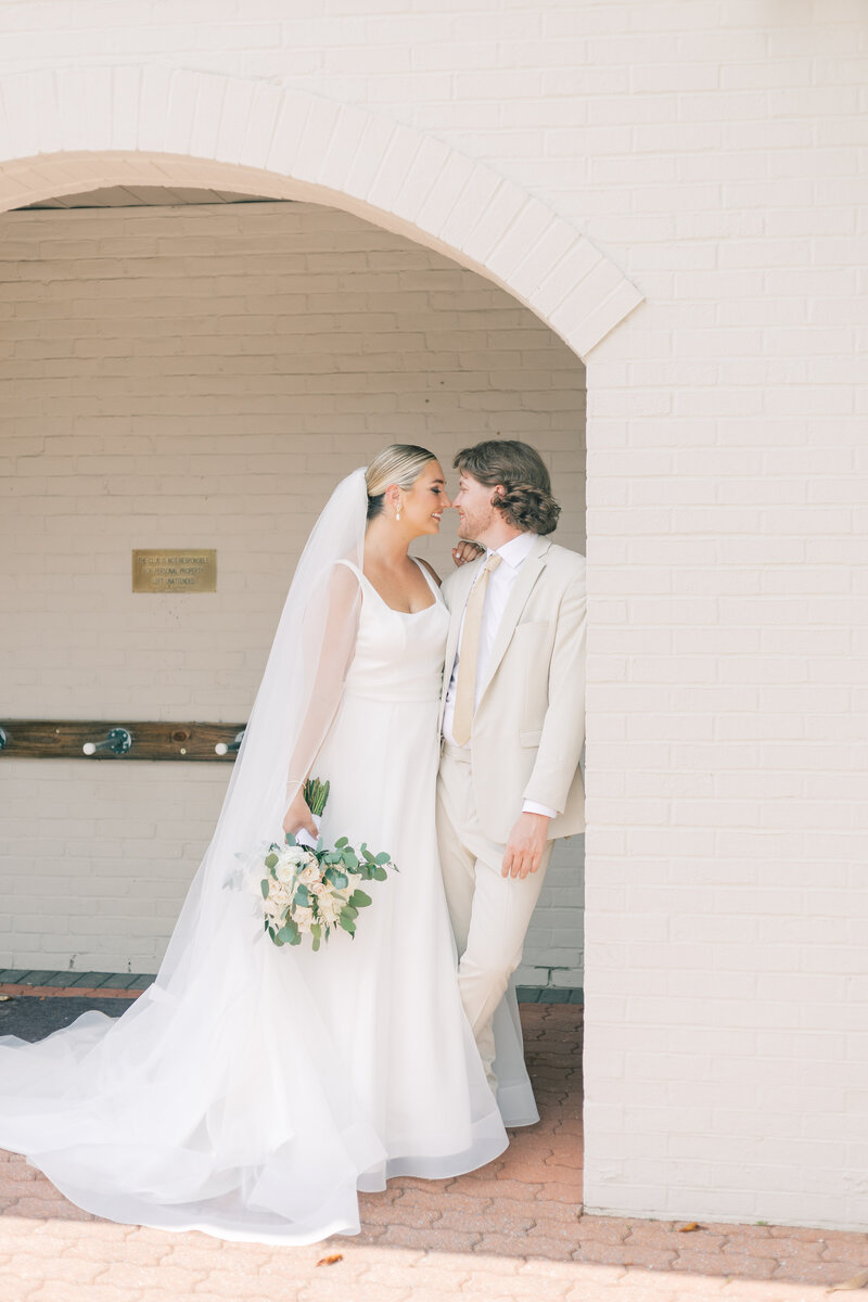 Couple standing under wedding arch on golf course in MD on wedding day