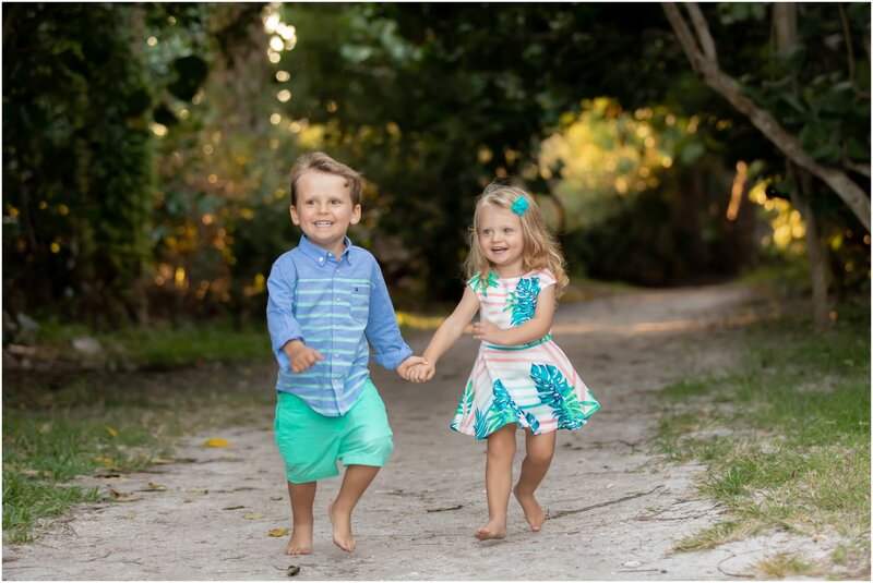 A young brother and sister running down the beach path holding hands