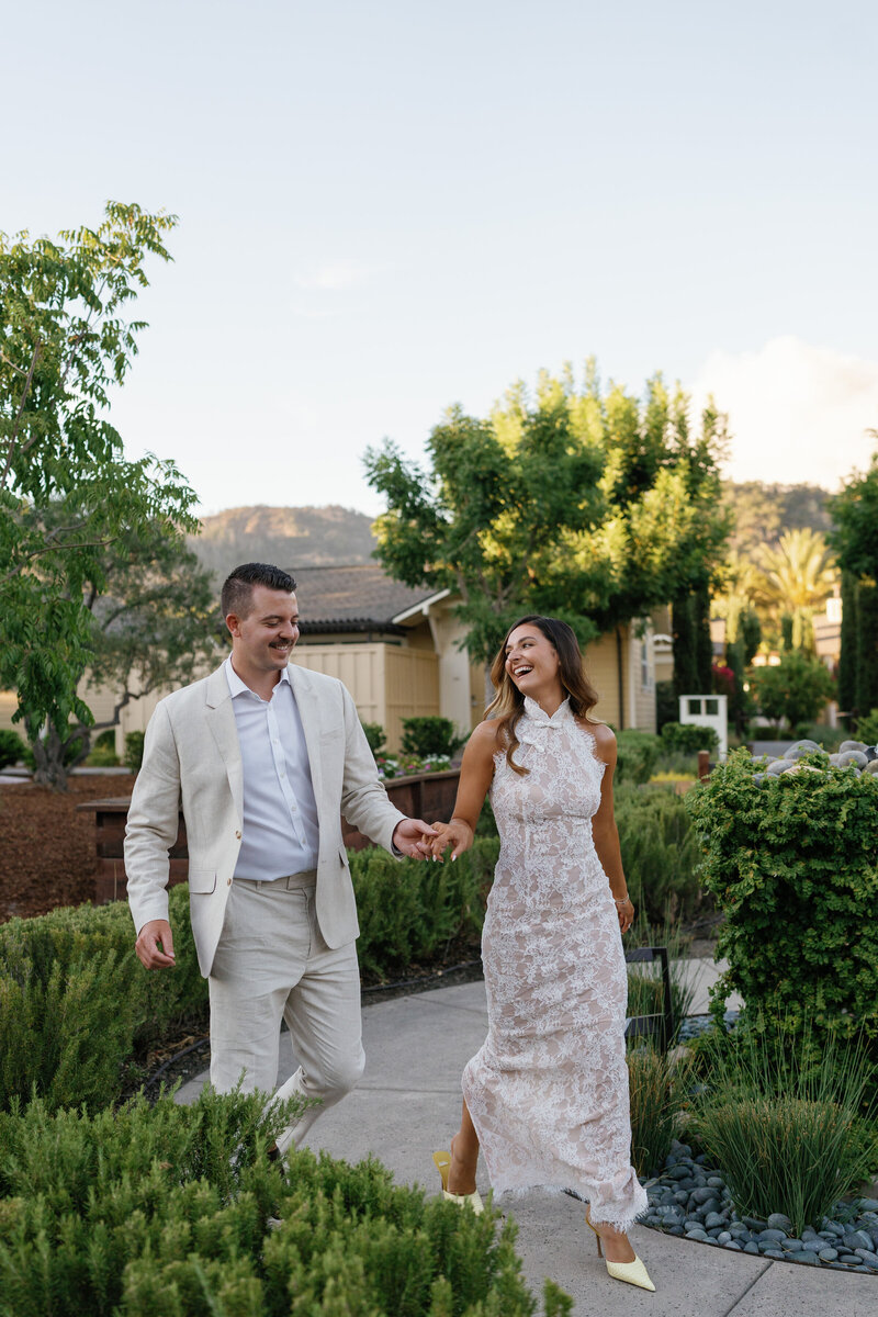 A beautifully set table featuring botanical-patterned linens, floral centerpieces, gold flatware, and green glassware.