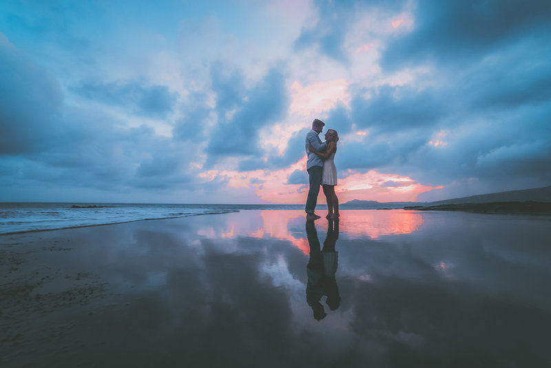 An engagement session in Oahu shows the reflections from the sky.