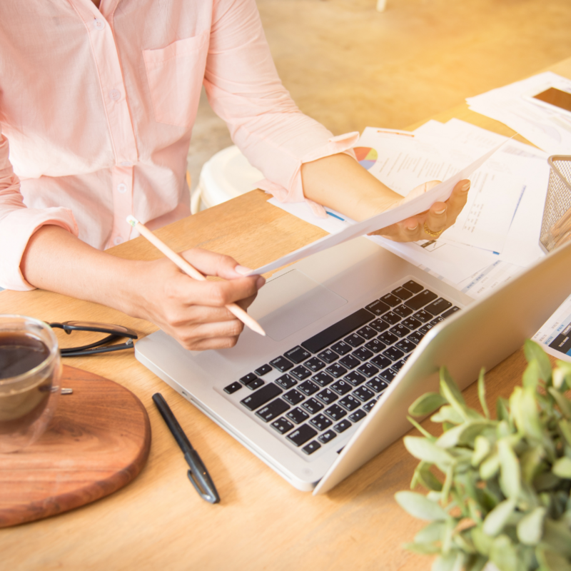 Photo of a person holding a paper in front of a laptop.