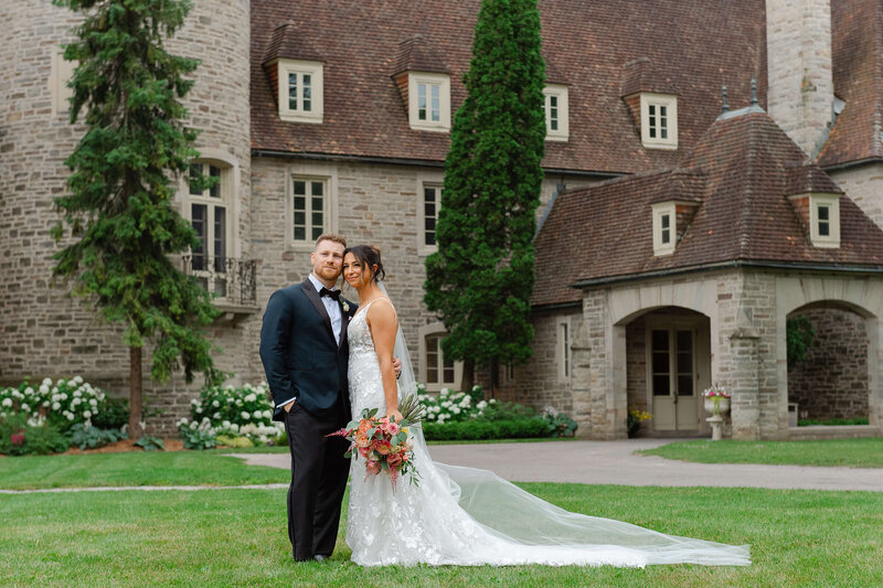 A bride and groom smiling outside Eaton Hall on their wedding day.  Captured by Ottawa wedding photographer JEMMAN Photography