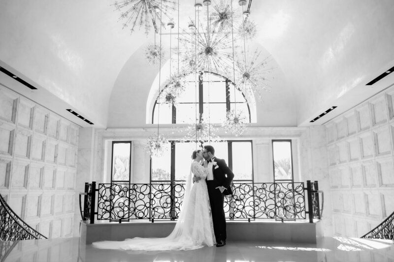 Black and white bride and groom portrait on the grand staircase at a wedding at the four seasons Orlando by Florida wedding photographer.