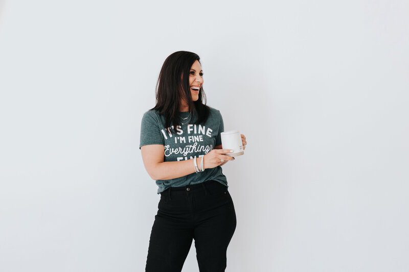 Christian woman holding a coffee cup wearing a  shirt that says "it's fine, I'm fine, everything is fine
