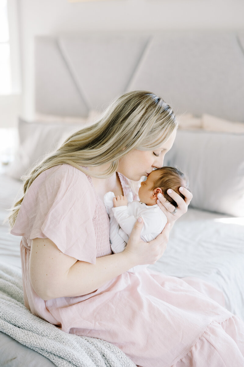 mom kissing newborn baby's forehead during an in home lifestyle newborn session