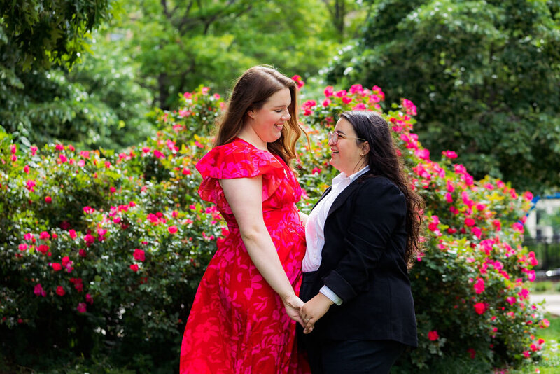 A couple holding hands and smiling at each other in a garden