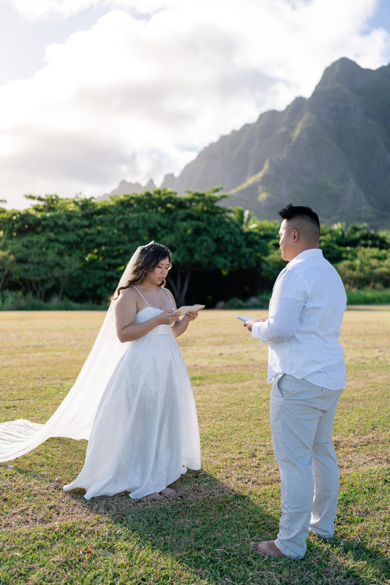 Oahu Hawaii elopement with bride and groom doing elopement ceremony vow exchange at Kualoa Regional Park.