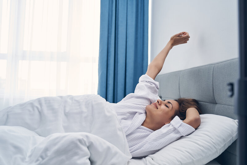 mom stretching, laying under weighted blanket to reduce stress for moms