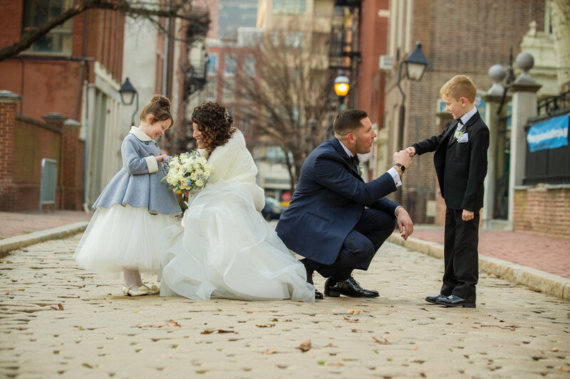Bride and groom kneeling to chat with the flower girl and ring bearer during their Philadelphia wedding.