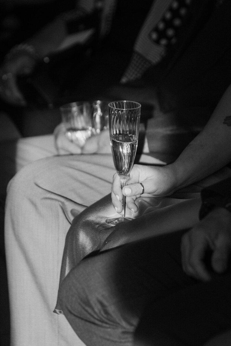 Two people sitting next to each other holding champagne glasses 