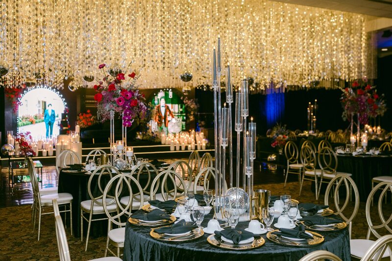 wide shot of black and white wedding reception with white chairs and white florals