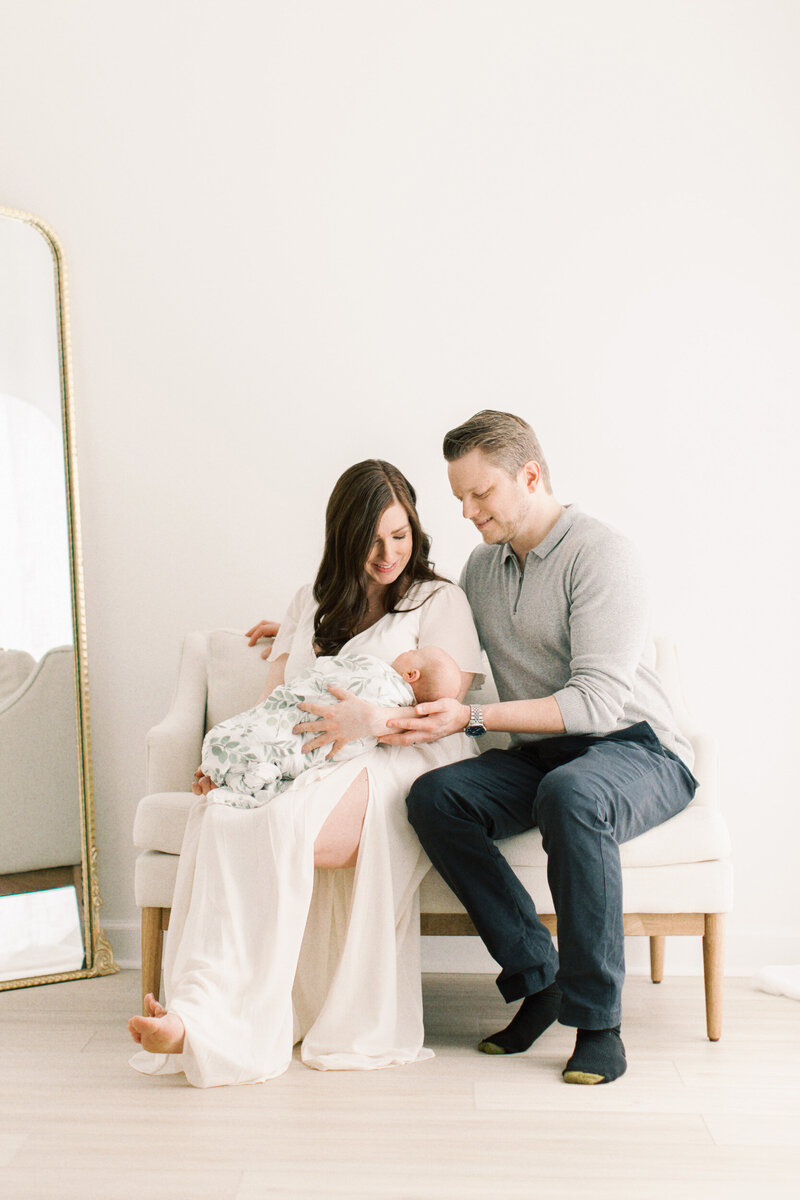 parents holding baby on couch in photography studio