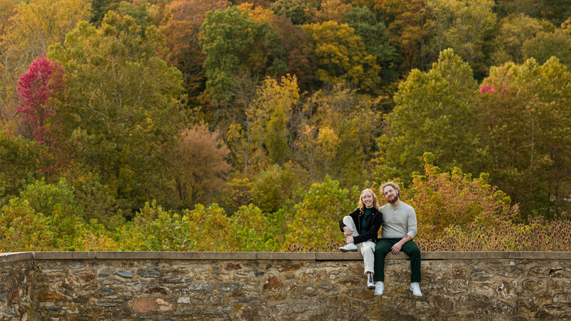 Couple sitting close together on an old stone wall at Valley Forge National Historical Park, sharing a quiet moment.