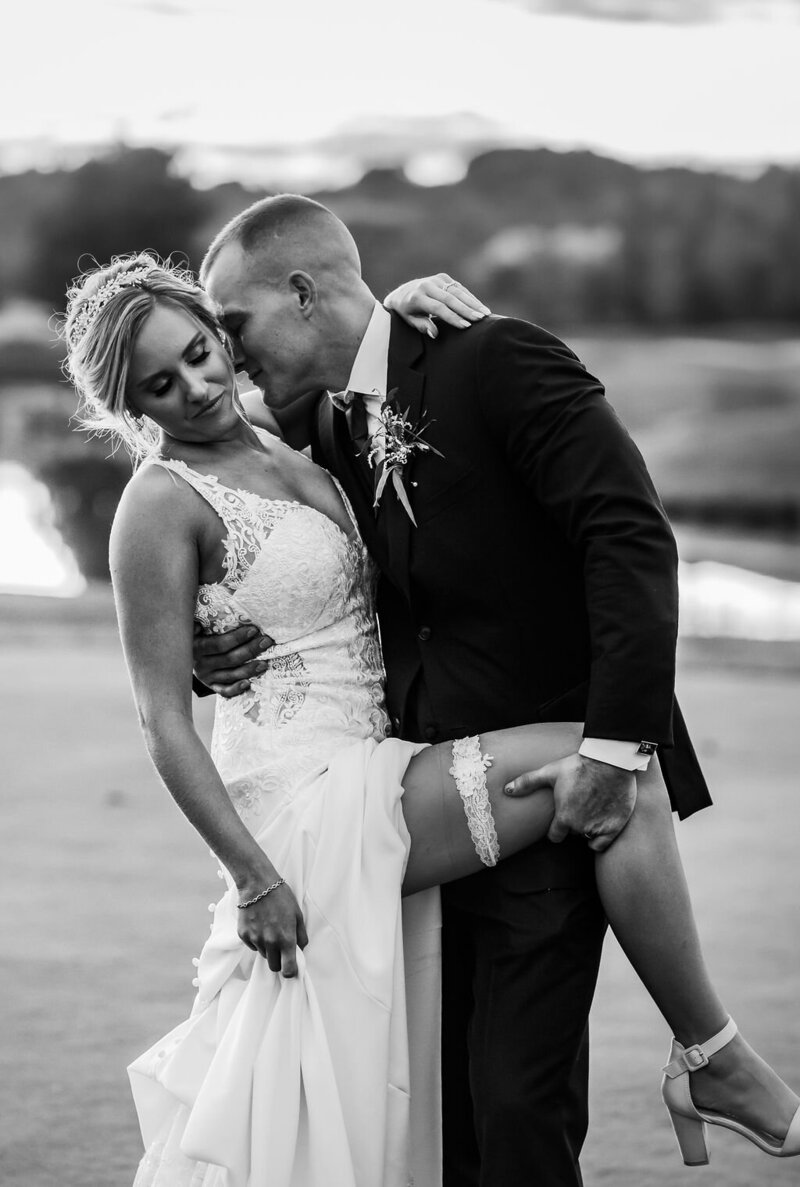 Black and white shot of groom kissing bride on golf course, photographed by Baltimore wedding photographer, Kimberly Dean