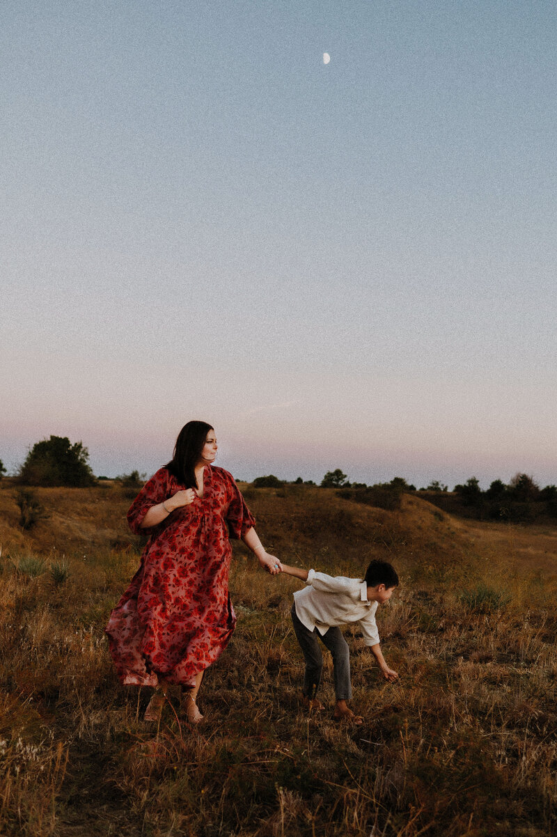 A mother holding hands with her son and wandering towards the sunset in Fort Worth, TX