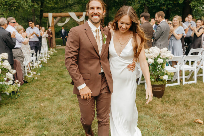 Bride walking arm in arm with her groom, laughing together after saying I do, captured by a Washington wedding photographer.