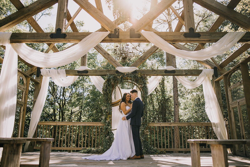 Bride and groom embrace under the warm sunlight in an old chapel.
