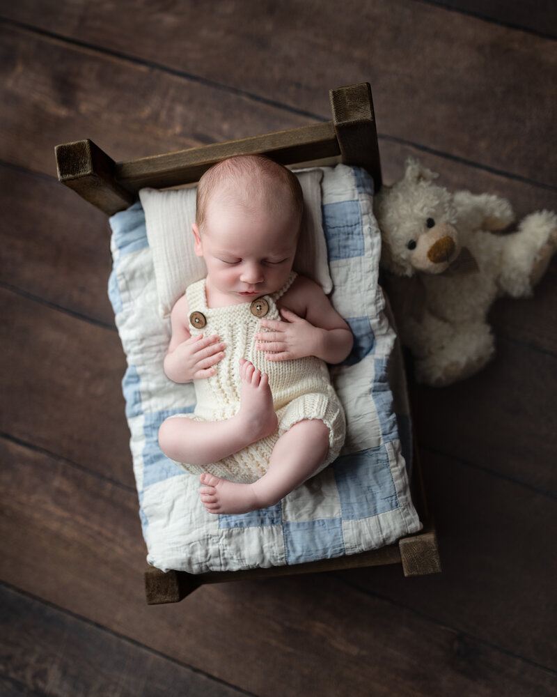 A classic newborn boy setup featuring textures, quilts, and timeless sleepy charm.