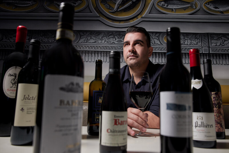 A man with various wine bottles in front of him