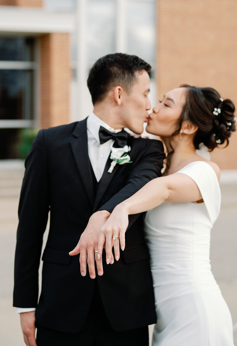 Newly weds showing off their wedding rings and kissing