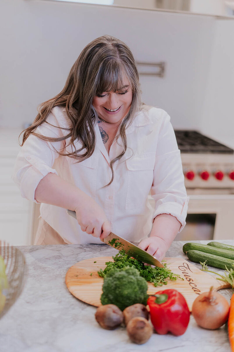 A cook in her kitchen smiles while chopping food for a branding photoshoot in Langley