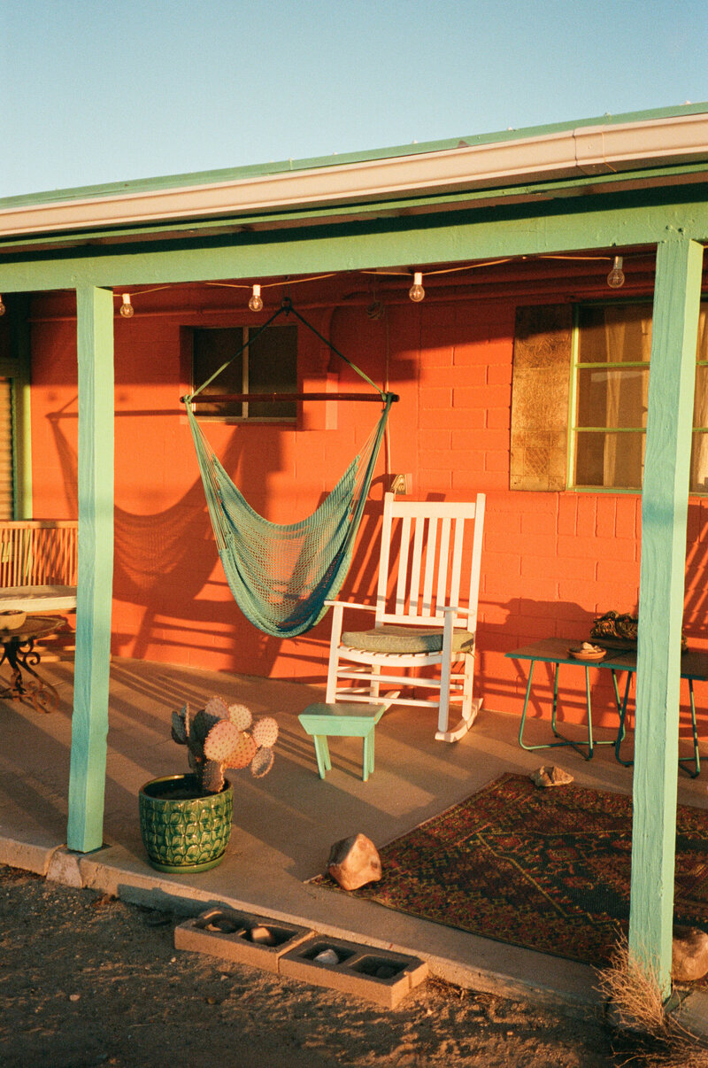 A hammock and chair on a small porch.