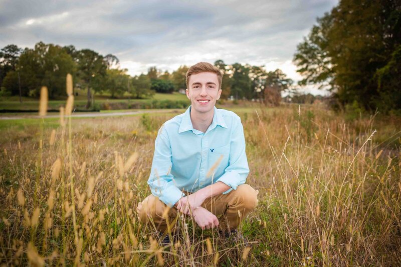 Senior portrait  of a boy in a field at sunset