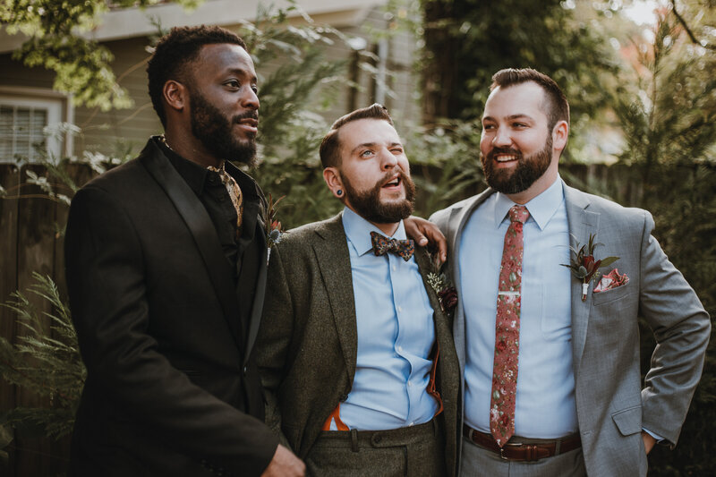 three groomsmen smiling outside