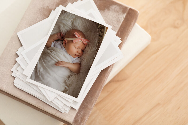 loose print mock ups of newborn baby images on top of pink album